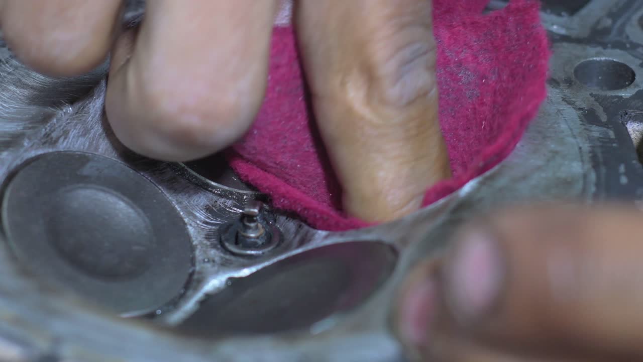 Close-up of mechanic’s hands cleaning motorbike engine new piston valves with cloth