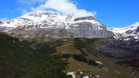 aerial view flying towards the snowy mountains and a refuge in the spanish pyrenees