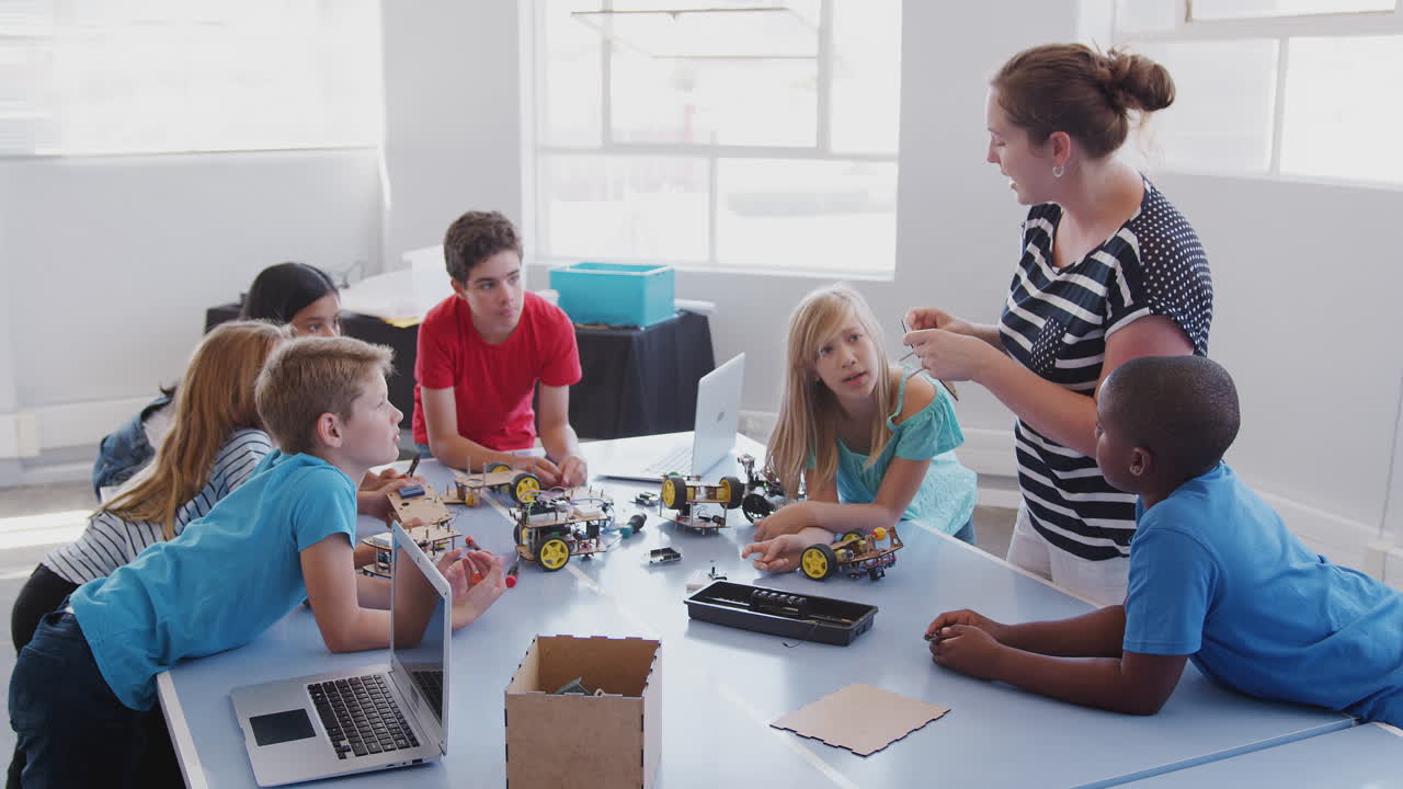 estudiantes con una maestra en una clase de codificación de computadoras después de la escuela aprendiendo a programar un vehículo robot