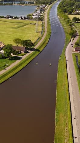 aerial view of rowing boats on a canal in a green landscape