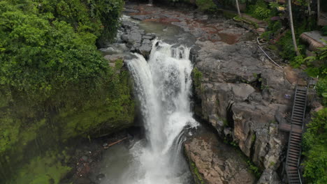 Aerial-dolly-ascending-shot-of-exotic-tropical-restaurant-at-the-top-of-a-large-waterfall-in-the-jungle-surrounded-by-rainforest