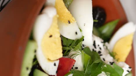 close-up of a fresh and healthy salad with hard-boiled eggs, feta cheese, and herbs