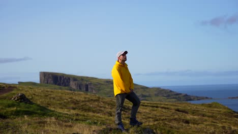 Carefree-man-inhales-fresh-air-while-stretching-his-arms-out,-Faroes