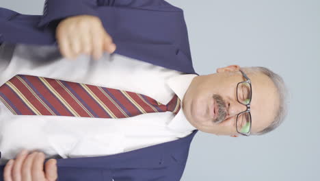 video vertical de un viejo hombre de negocios oliendo sudor expresando negativo a la cámara.