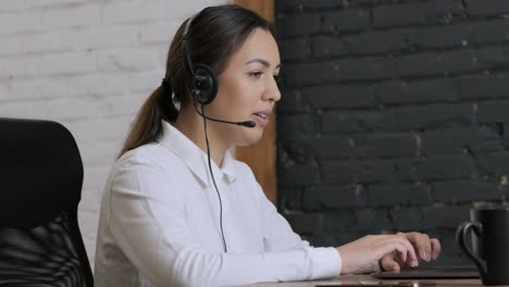 smiling woman call centre operator, customer support agent wears headset consults client online typing on laptop, talk in internet computer chat, helpline operator secretary make conference video call