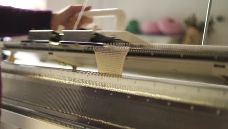 female hands working on weaving machine in workshop. knitting woolen fabric