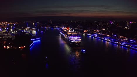 queen mary 2 cruise ship in hamburg harbour at cruise days during the night at blue hour with blue light show across the city of hamburg