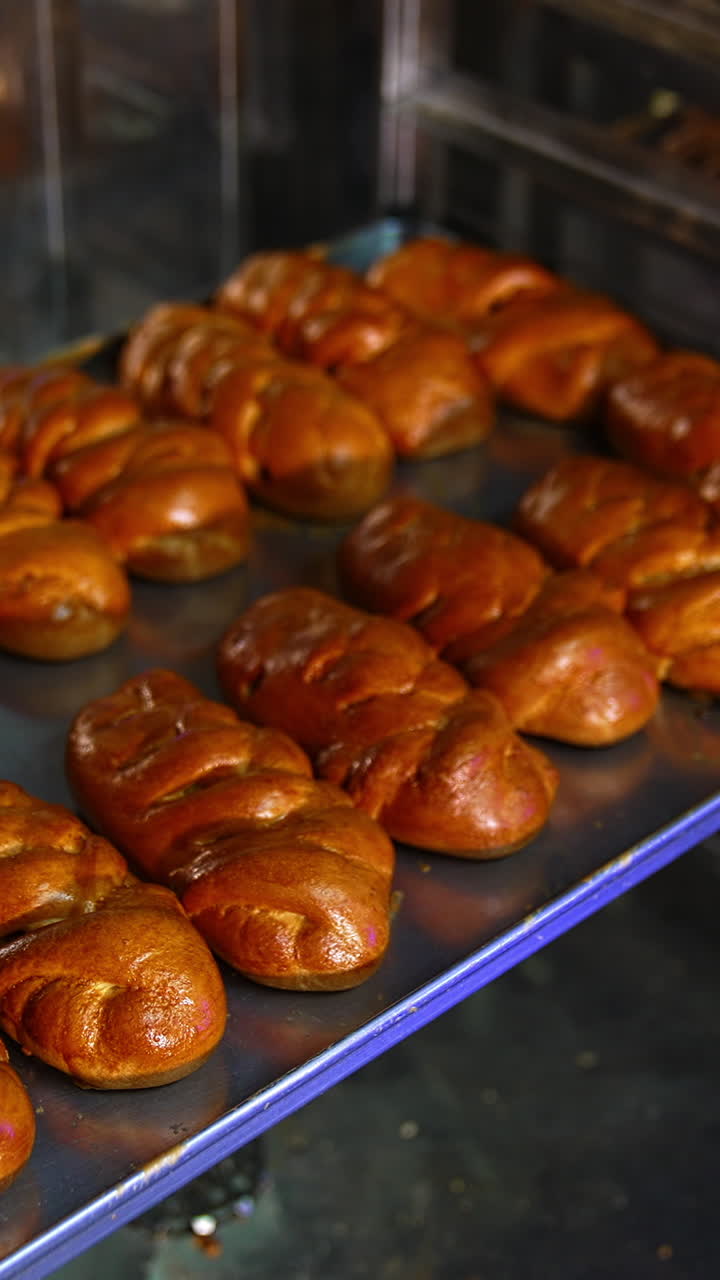 Freshly baked brown pastry being taken out off the oven. Confectionary worker opens the oven and pulls the baking sheet with sweets out. Vertical video