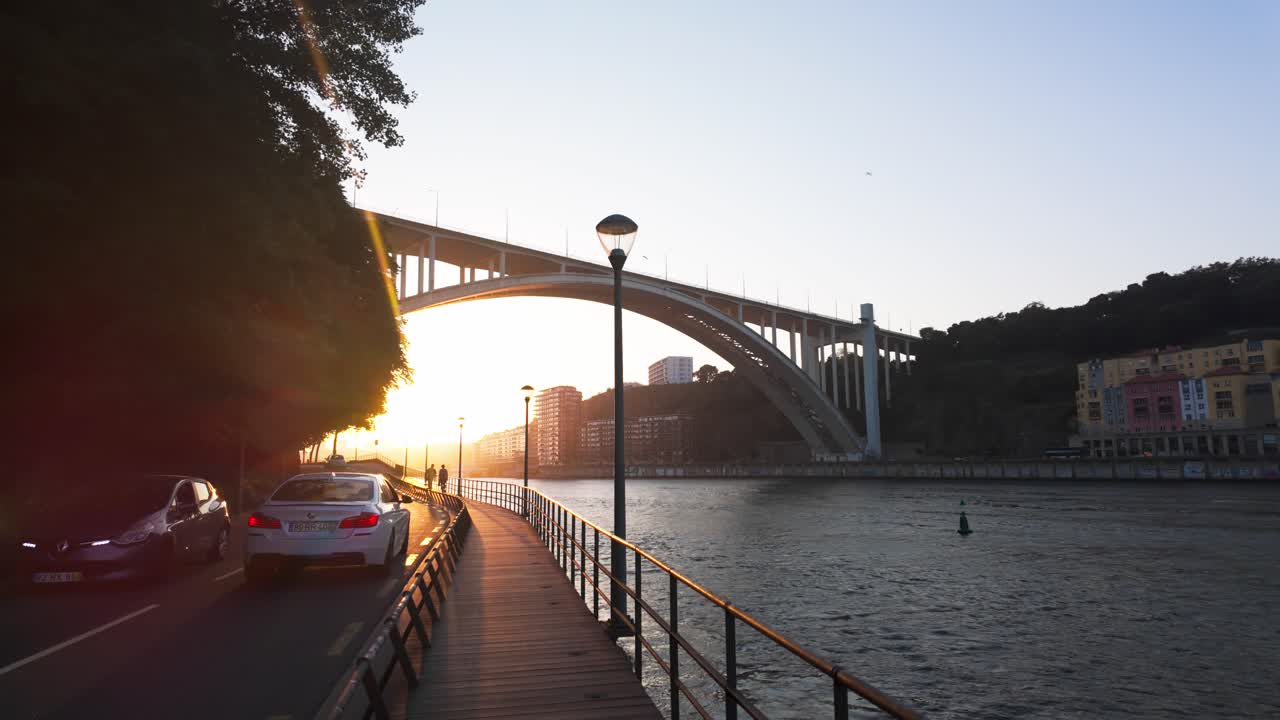 A white car drives on a sunlit road by a lush hillside in Vila Nova de Gaia near the Douro River