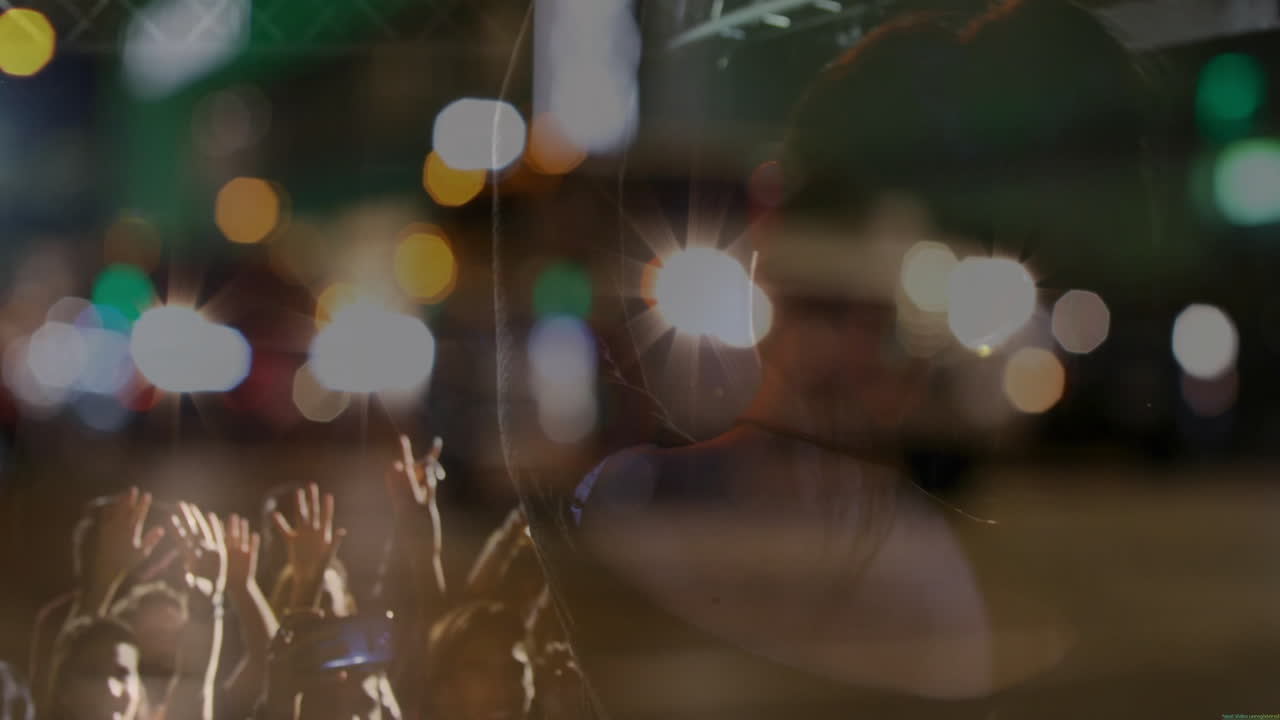 performer raising arm engaging crowd at night concert under stage lights, with music notes overlay