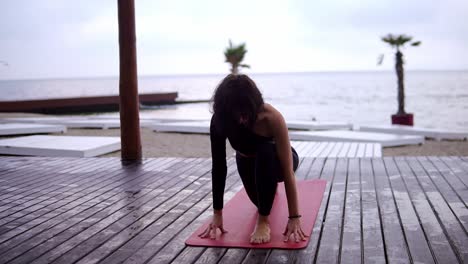 Girl-Is-Doing-Yoga-On-Wooden-Floor-On-The-Beach,-The-Girl-Performs-Yoga-Stands-And-Elements