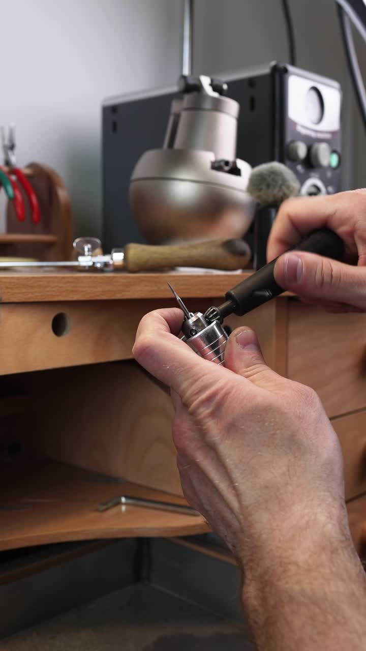 Jeweler's Hands Preparing a Rotary Tool for Detailed Work