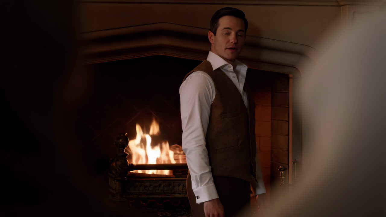 Man in vest standing in front of a fireplace