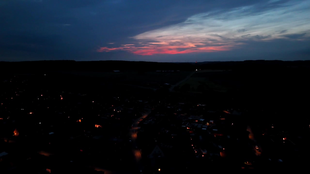 Quiet Golden sunset with pink sky at dusk. Lighting streets and roads with houses and homes in american town. Aerial forward dolly wide shot. Night scene in suburbia of United States.