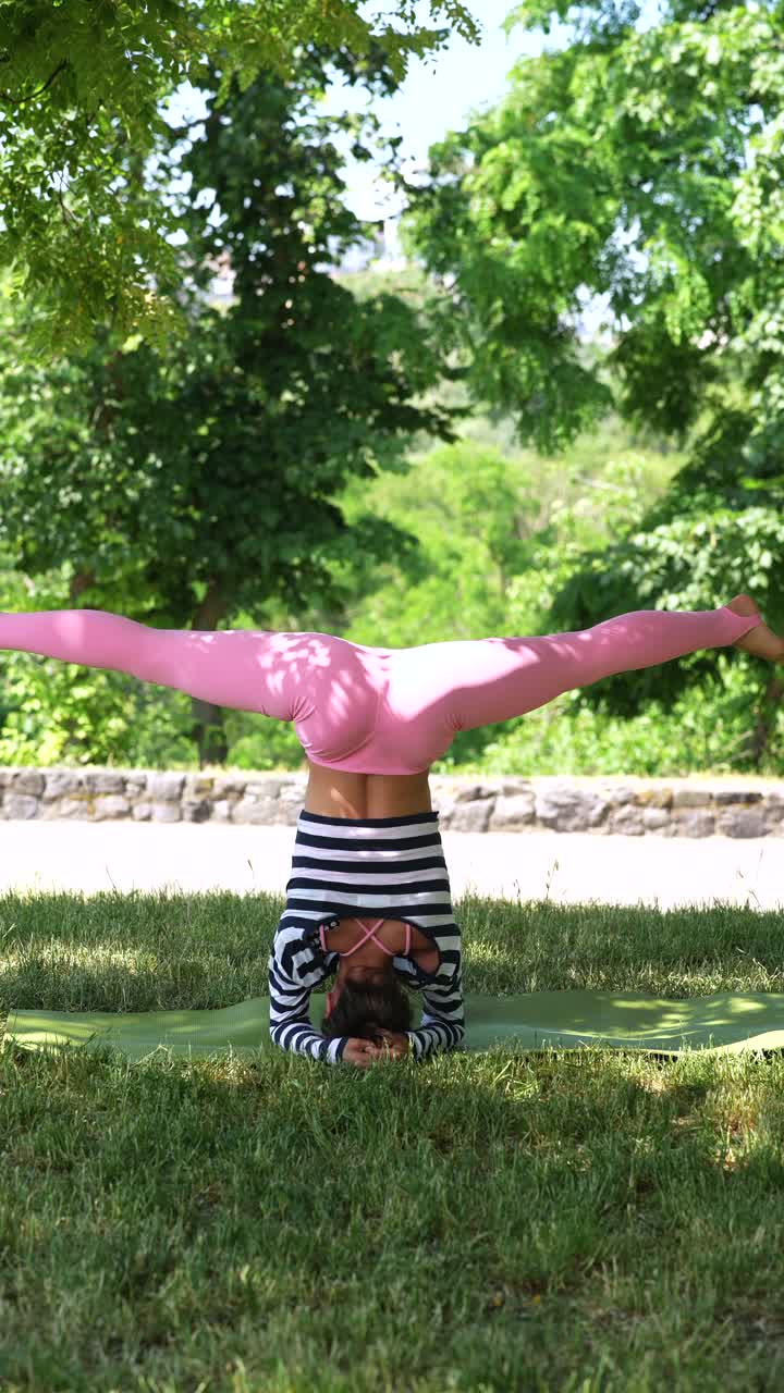 mujer practicando la postura de yoga de pie de cabeza en un parque