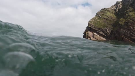 Rocky-Coastal-Landscape-on-Beach-as-Camera-Floats-and-Dips-Underwater