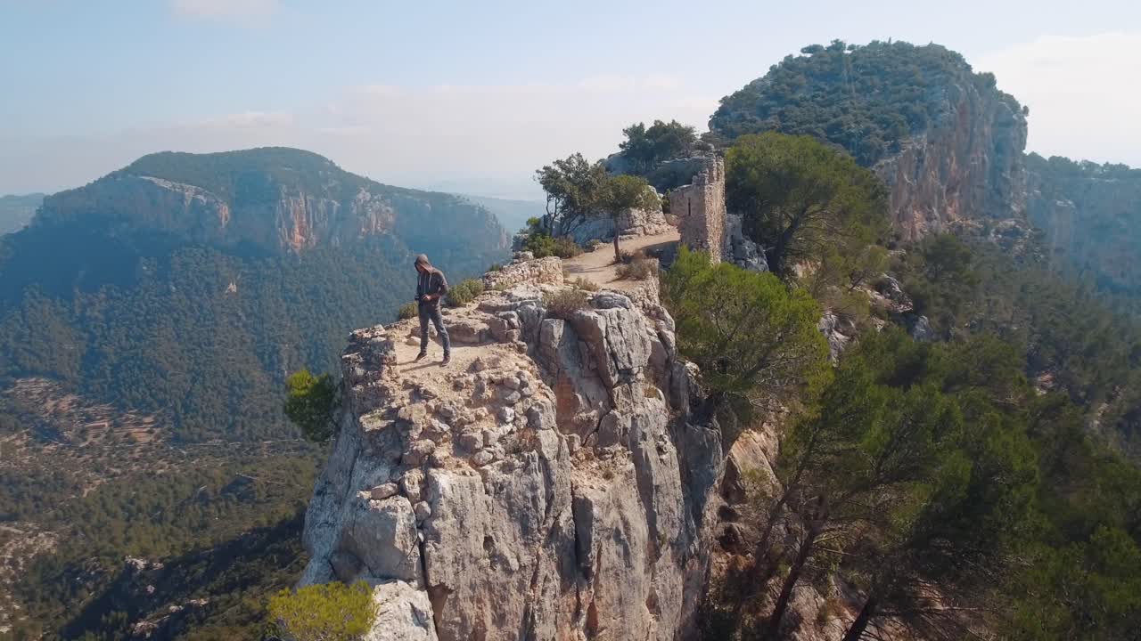 Aerial shot in 4k of a photographer standing on a mountains and takes a picture of a breathtaking landscape.