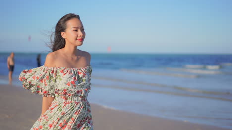 slow-motion of asian lady walking along the beach in thailand wearing a long sundress, blurred background