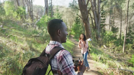 Smiling-diverse-couple-taking-photo-and-hiking-in-countryside