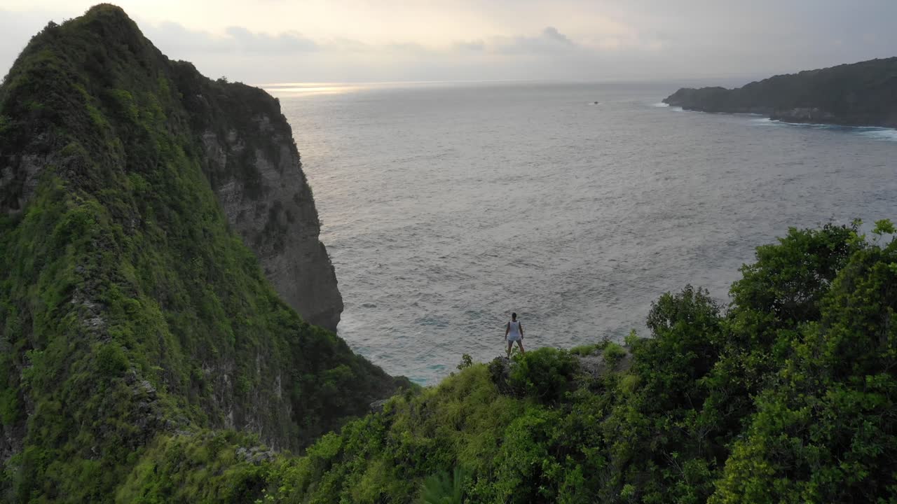 concepto de éxito empresarial joven exitoso parado en la cima de los acantilados marinos durante el amanecer