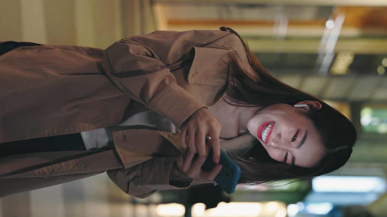Woman Celebrating with Phone in a Mall at Night