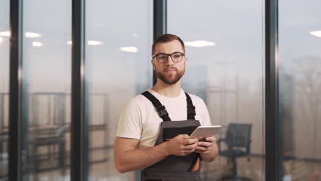 Retrato-De-Un-Hombre-Adulto-Con-Uniforme-De-Trabajo-Con-Una-Tableta-De-Traducción-Mirando-La-Cámara-Y-Sonriéndole