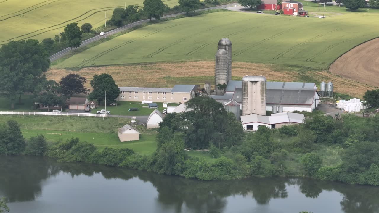 Traditional American farmer house with silo storage, barn, stable and machinery. Sunny summer day in east America. Aerial zoom shot. Suburb rural area of city