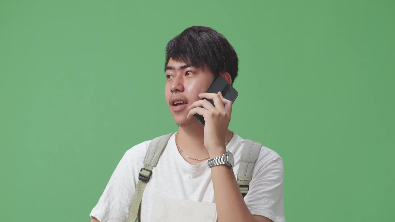 녹색 스크린 스튜디오에서 휴대전화로 대화하는 아시아 남성 학생의 클로즈업