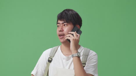 close up of asian man student talking on mobile phone in green screen studio