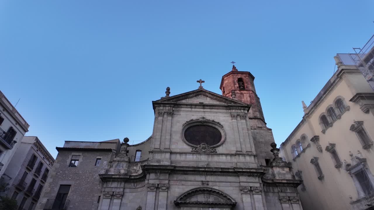 Plano frontal em câmera lenta da fachada de uma igreja histórica no centro antigo de Barcelona.