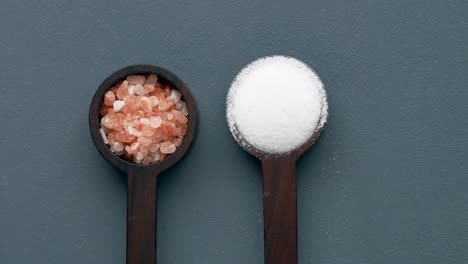 close-up of pink himalayan salt and white table salt in wooden spoons