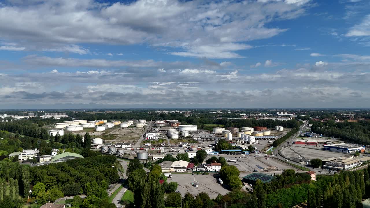 Panoramic aerial view of inactive refinery sprawling industrial complex featuring numerous storage tanks and processing facilities under a partly cloudy sky in Cremona Lombardy Italy