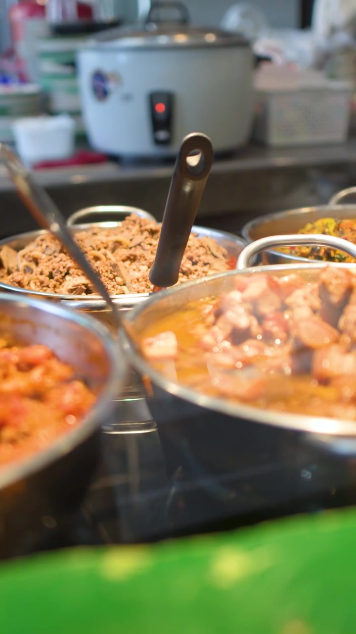 Inquadratura media statica di vari curry thailandesi del nord e stufati di maiale piccanti in pentole di metallo