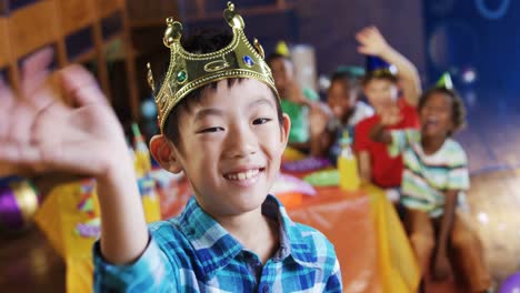 boy in crown waving his hand during birthday party 4k