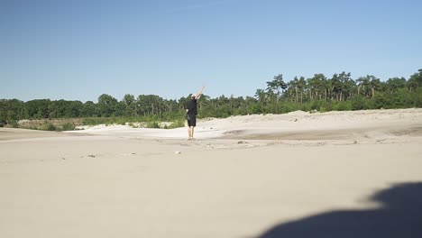 young hispanic male running around and throwing stones at a beach from a lake in the belgian forest