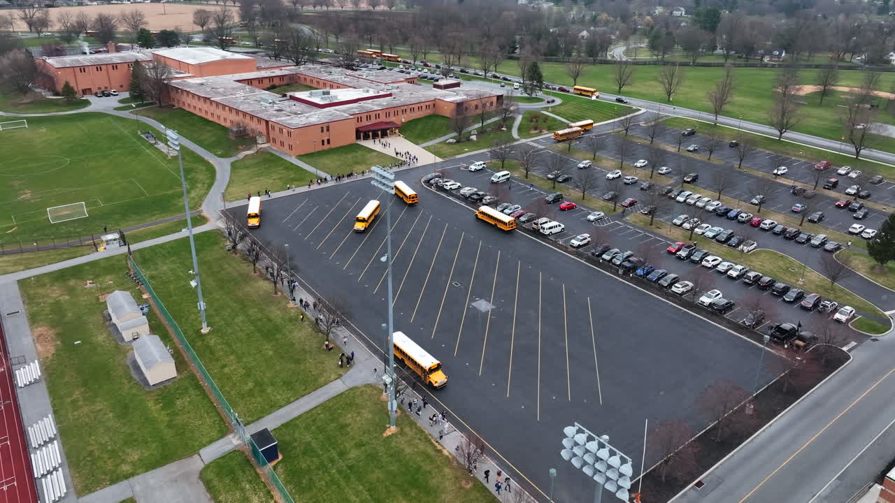 Aerial of American school campus with yellow school bus arrival and departure