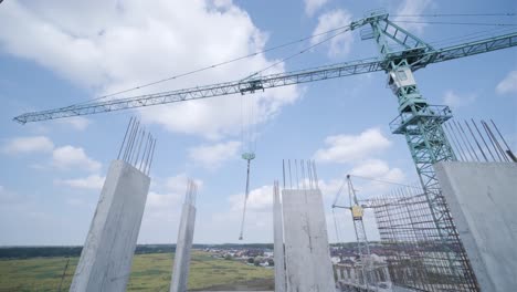 tower cranes work on the construction of brick residential buildings against the background of a blue sky.