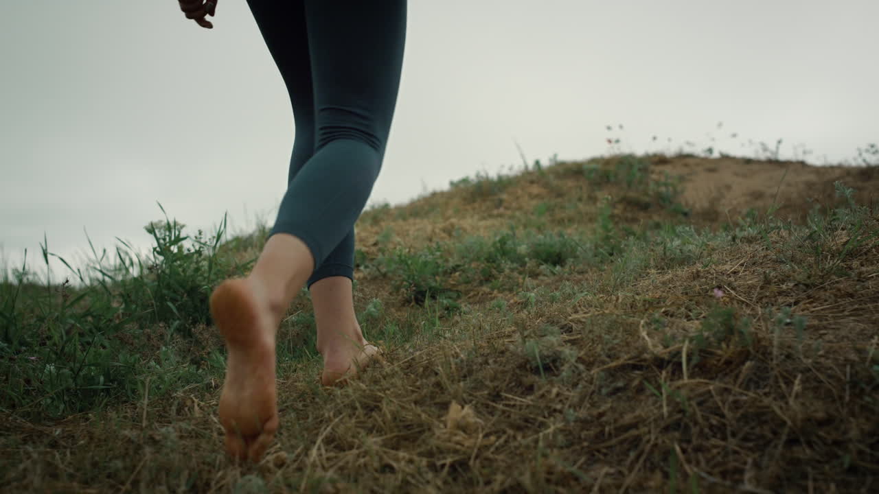 Sporty girl going hill edge closeup. Woman legs walking hilltop cloudy day.
