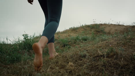 sporty girl going hill edge closeup. woman legs walking hilltop cloudy day.