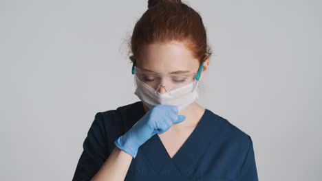 redheaded doctor in front of camera on gray background.