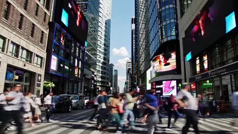 crowded urban street with pedestrians crossing and bright digital displays in the city center during midday