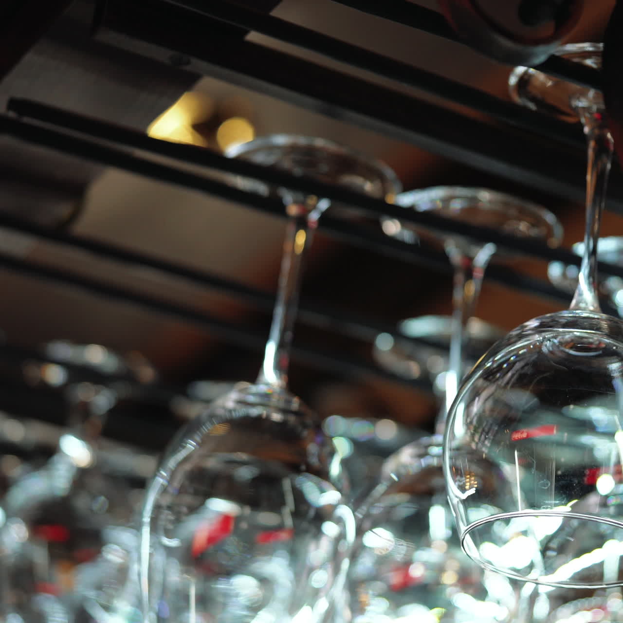 Bartender pendura copos. Taças de vinho penduradas em um suporte em um bar. Vídeo quadrado