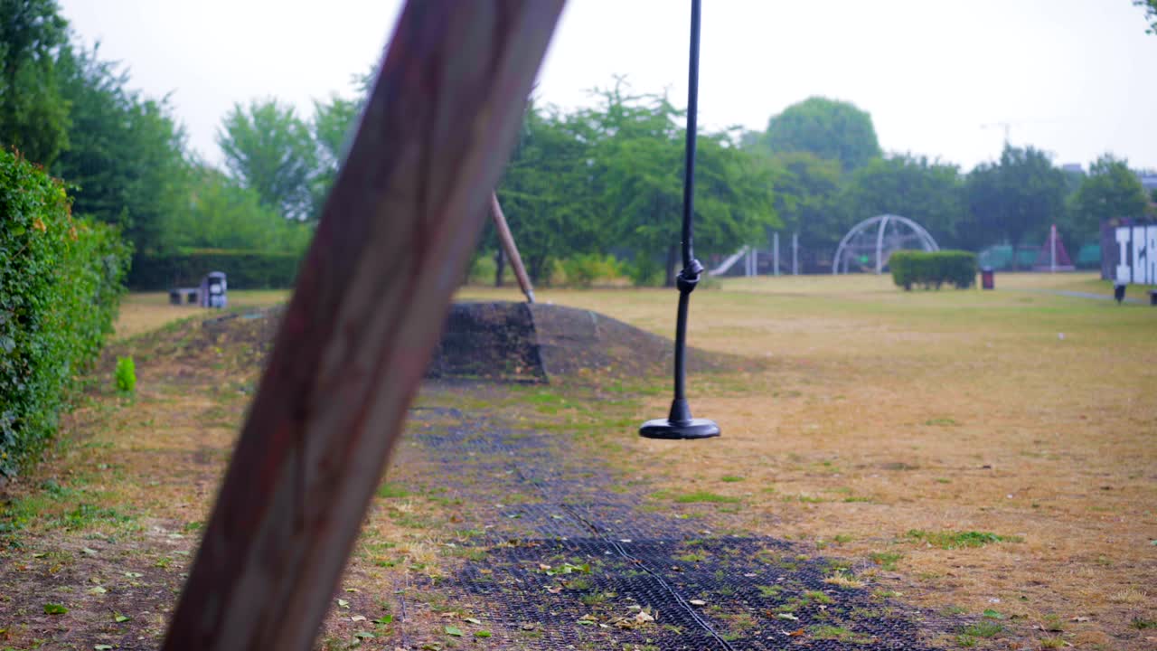 tirolesa vacía que se balancea lentamente en un parque infantil, bajo la lluvia, escena vacía de bloqueo