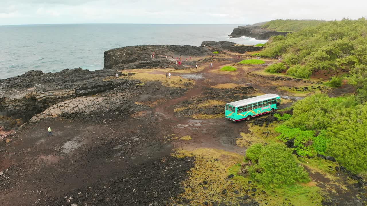 관광객들이 모리셔스의 퐁 자연을 볼 때 절벽에 주차된 청록색 버스