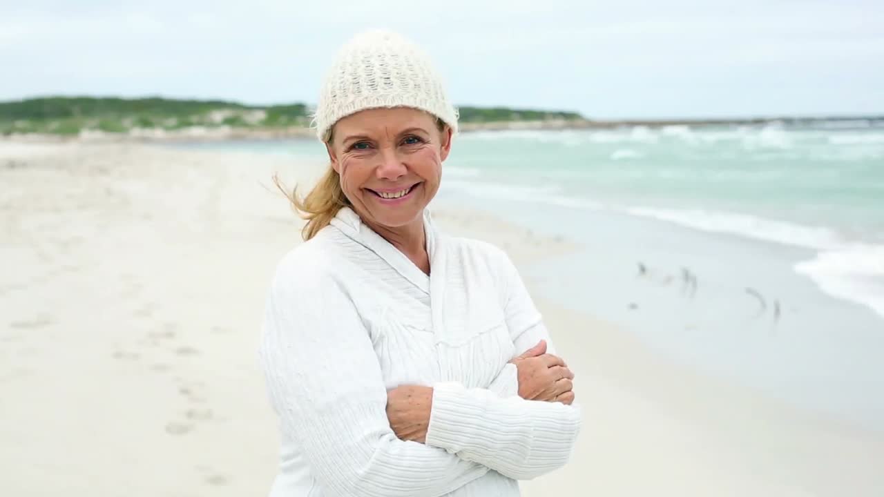 Retired woman on the beach looking out to sea