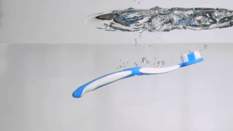 une brosse à dents bleue dans un mouvement super lent tombant dans l'eau