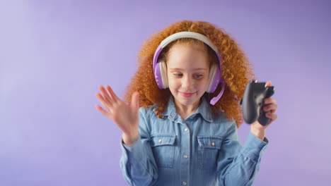 Studio-Shot-Of-Girl-Wearing-Headset-Gaming-With-Controller-Against-Purple-Background