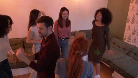 excited friends dancing while enjoying weekend party in living room at home