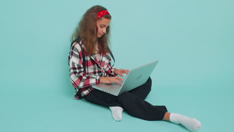 teenager child girl works on laptop pc, sends messages, makes online purchases, watching movies