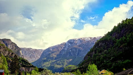 Dense-clouds-flying-over-mountains-during-sunny-day-in-scenery-scene---time-lapse